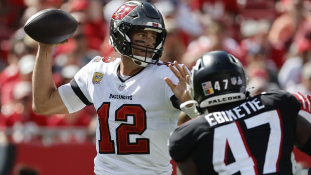 Buccaneers quarterback Tom Brady throws a pass while Falcons defensive end Arnold Ebiketie rushes him.
